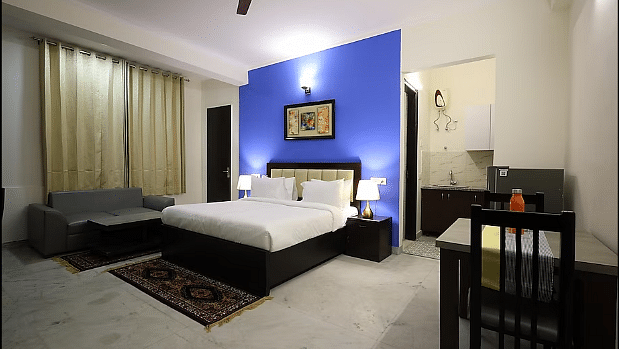 A hotel room featuring a large bed with a blue accent wall, modern furnishings and a kitchen area - Lime Tree Golf View, Golf Course Road