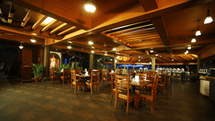 Table arrangement at Southern Express, Uday Suites featuring wooden ceiling and ambient lighting and four chairs placed around each of the square tables