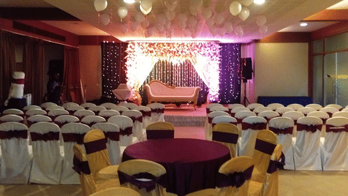 A decorated Bougainvillea hall at Uday Suites features rows of chairs facing a decorated stage with a sofa