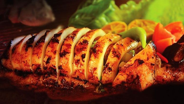 Grilled, sliced calamari served on the platter with vibrant green lettuce and colourful red and yellow bell peppers.