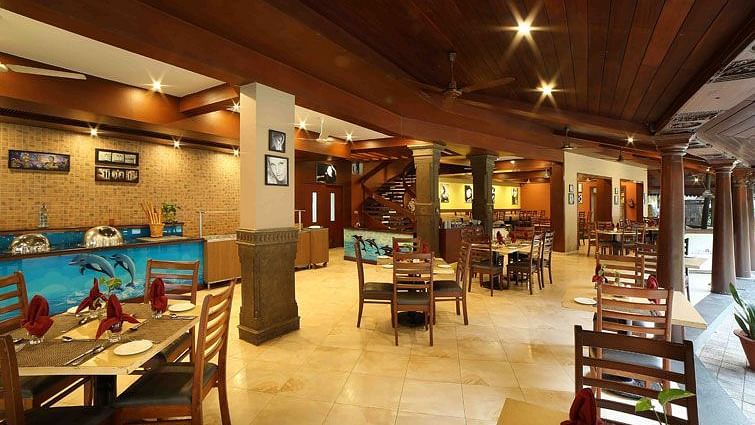 The courtyard at Uday Samudra Leisure Beach Hotel features wooden beams, tiled floors, and dining tables set and ready for guests.