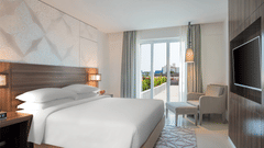 King Room with a balcony decked with a plush bed, couch and television at The Residency Towers Rameswaram