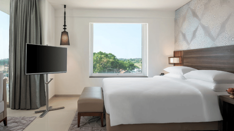 King Room with pool view arrayed with a plush bed and television at The Residency Towers Rameswaram