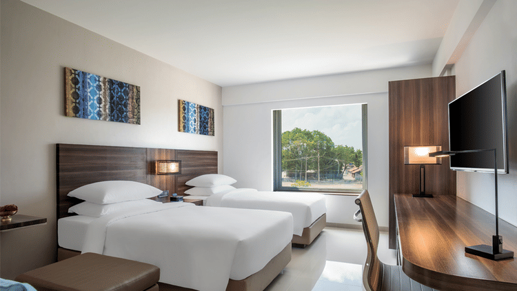 Standard twin room decked with two beds, television and a working desk at The Residency Towers Rameswaram