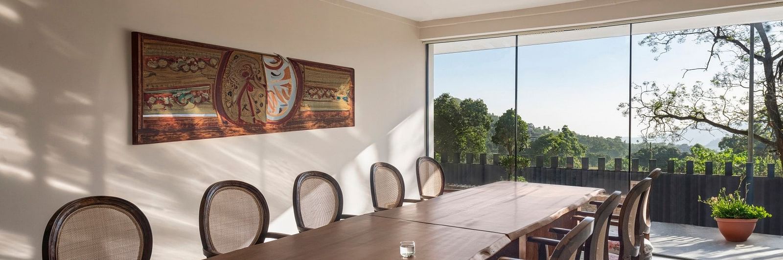 A meeting room with a long table in front of a glass door opening to a lush green garden - The Samai, Bhimtal