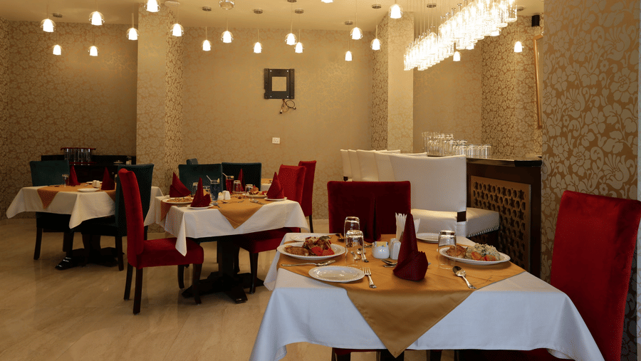 A dining area at Comfort Inn Sapphire by Eastlynn Collections, Jaipur with tables, chairs, lighting, and arranged seating layout.