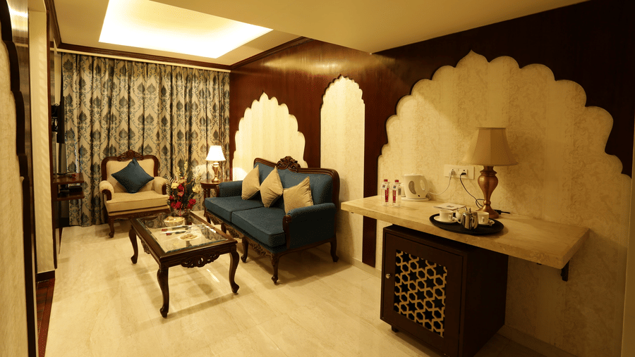 A sitting area at Comfort Inn Sapphire by Eastlynn Collections, Jaipur with chairs, table, sofa, cabinet, and lighting.