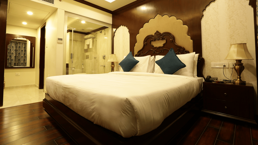 A bedroom at Comfort Inn Sapphire by Eastlynn Collections, Jaipur with king size bed, headboard design, side tables, lamps, and wooden flooring.