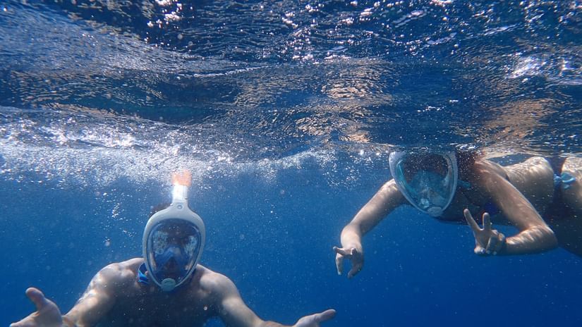 an overview of two people snorkelling and posing for a picture underwater.