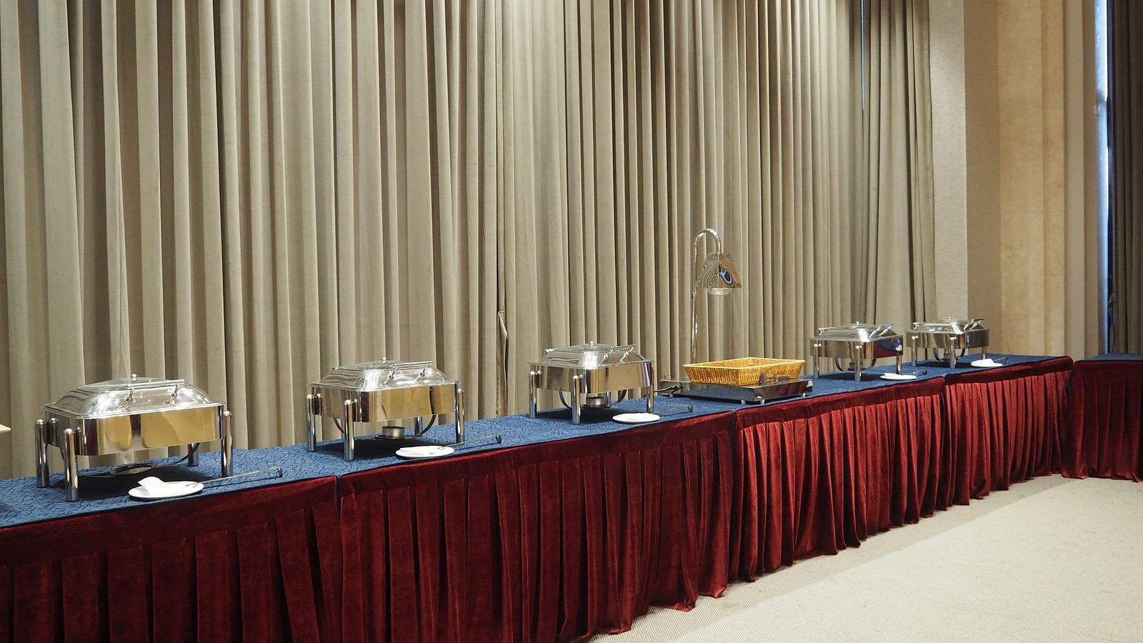 A buffet table with food and drinks in a hall with curtained windows - Club Charholi, Pune 