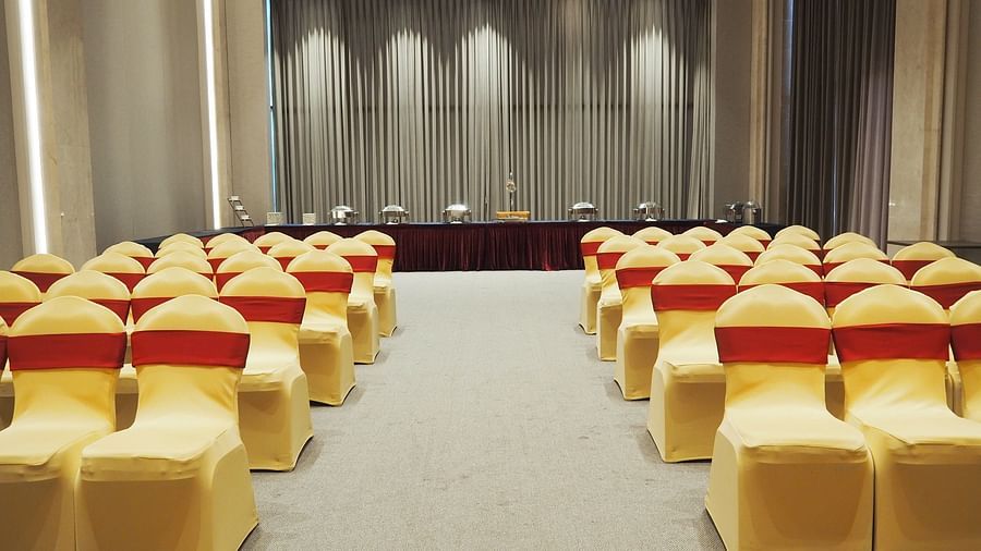 A stage with curtains and spotlights, viewed from rows of empty chairs - Club Charholi, Pune 