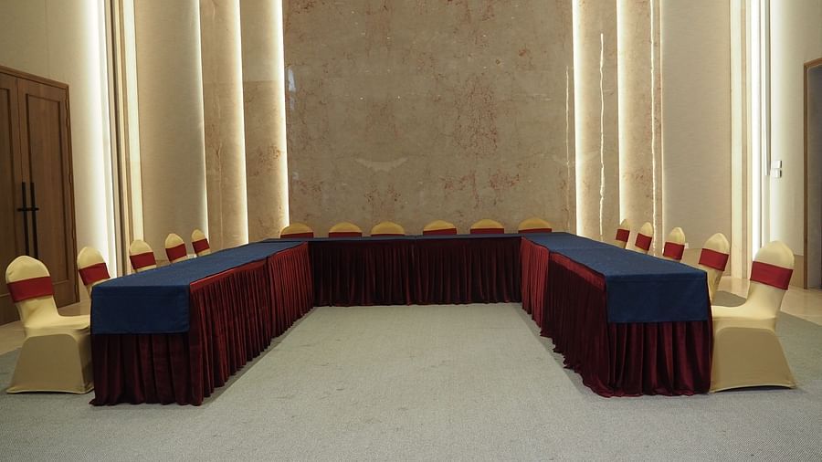 A U-shaped table with blue cloth and chairs in a grand, symmetrical hall - Club Charholi, Pune 