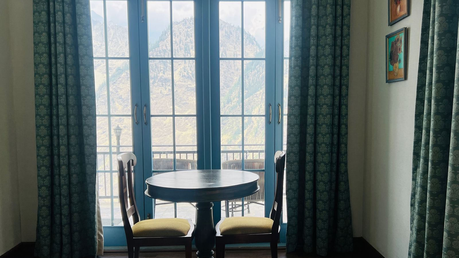A two-seater round table near a large window  | Faraway Cottages, Auli