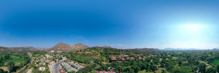 A scenic view showcasing charming houses and a luxurious resort, featuring an open hall that overlooks a clear blue sky, creating a serene atmosphere