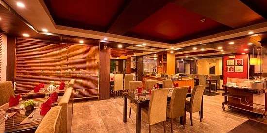 Renest Hotel Manali - Interior view of the restaurant featuring numerous seating options in brown and red decor 