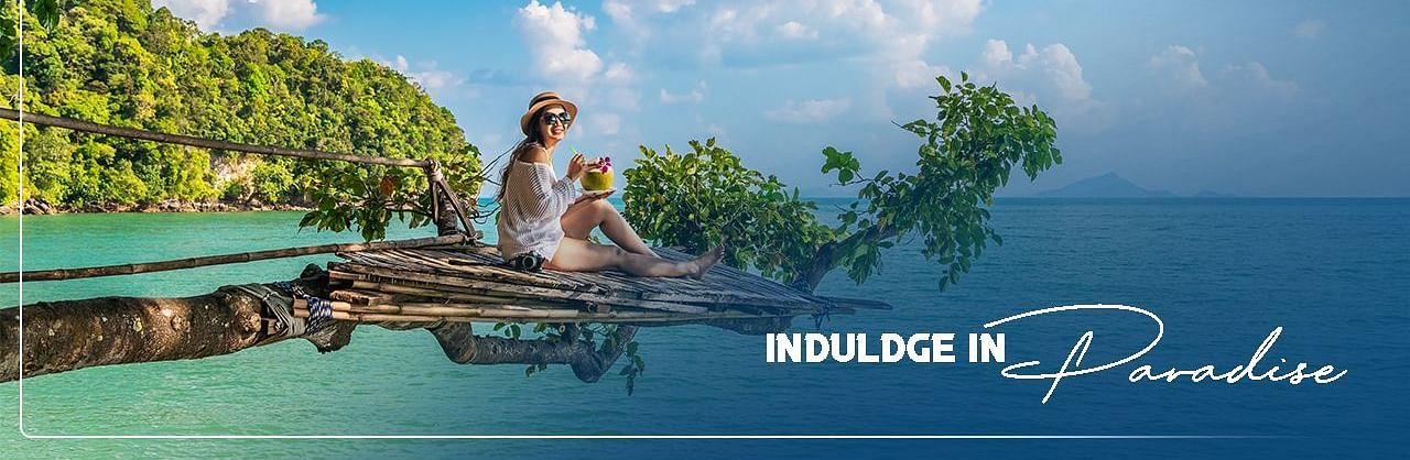 Woman traveller with scenic ocean and trees background and the text, Indulge in Paradise.