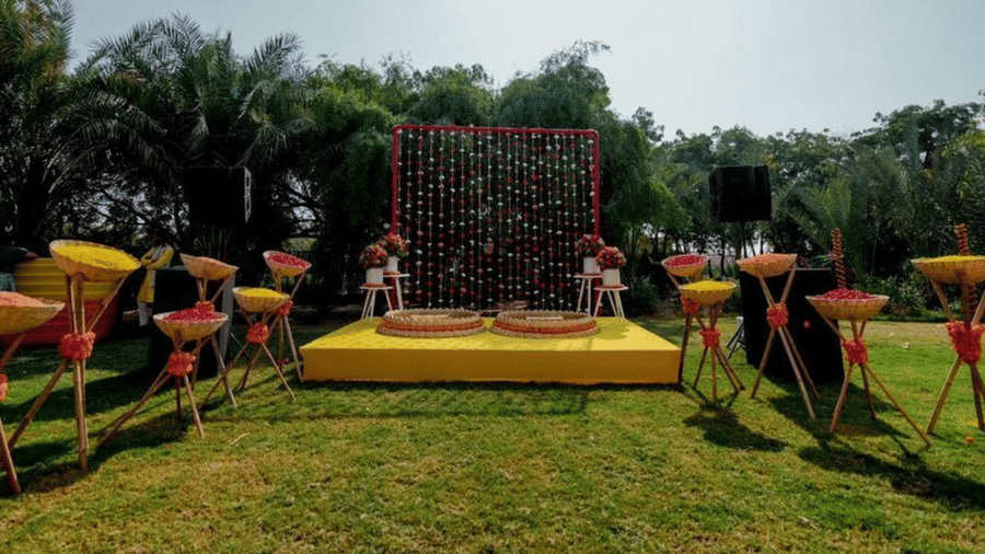 Outdoor wedding stage fully decorated at The Ummed Jodhpur, with a floral backdrop, colorful seating arrangements, and a lush green lawn.
