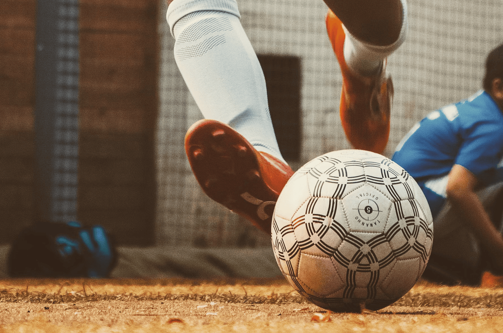 A worn soccer ball rests on the ground, with a foot visible, suggesting a game or practice at Nirantara Resort & Spa.