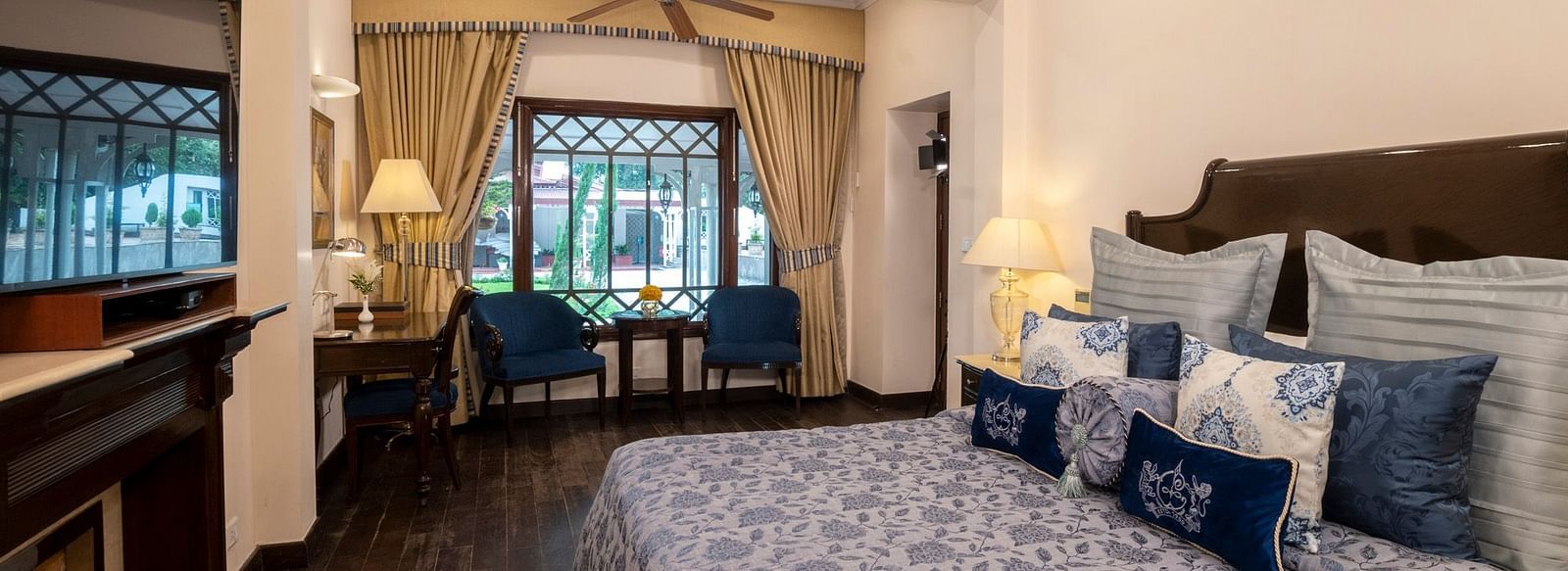 view of the king sized bed and the TV with the seating area near the window at the Claridges Nabha Residence, Mussoorie