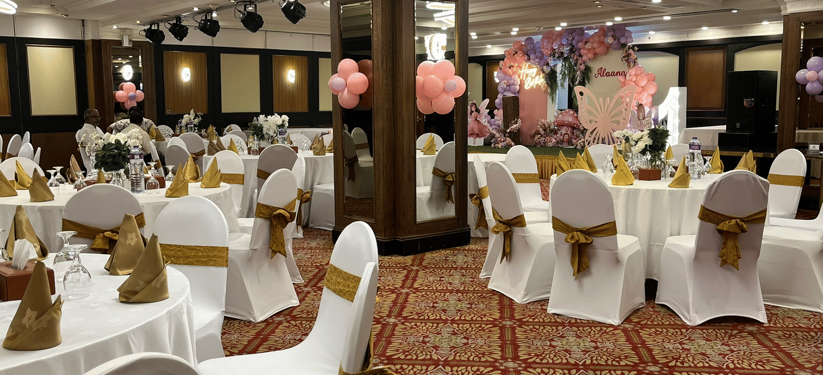 Indoor banquet hall with white chairs and round tables at Marco Polo Hotel.