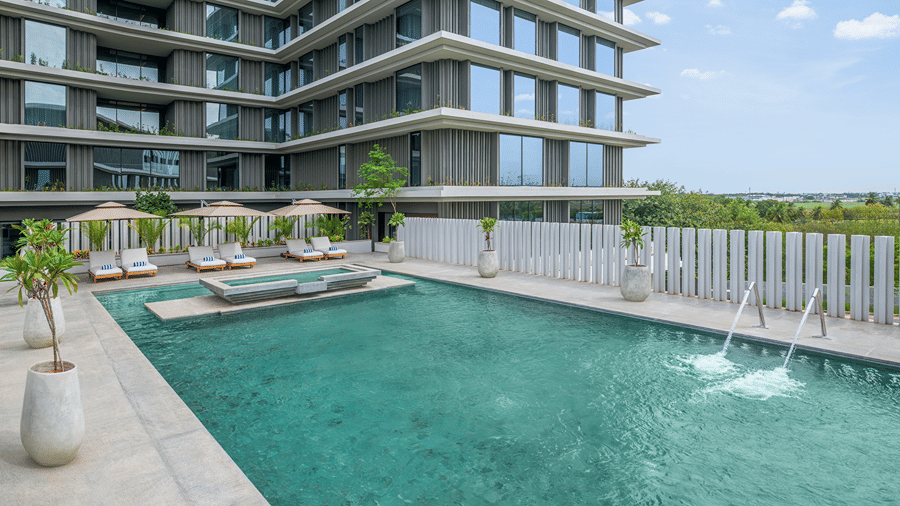 Rooftop swimming pool with loungers and a view of the building against the sky at The Residency Signature Madurai.
