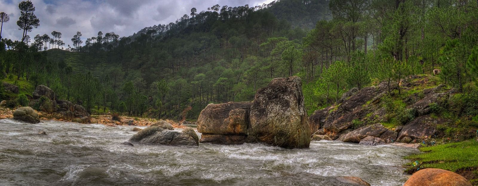 An image of a stream filled with stones and a mountain at the distance