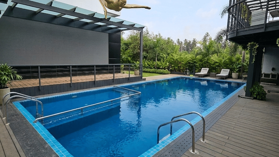 An outdoor swimming pool with a wooden deck and a gold sculpture on the building at BluSalzz Collection - Casa Onze, Arpora.