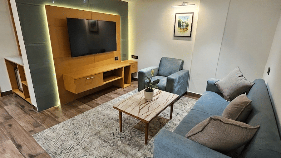 A living room space with a grey sofa, coffee table, and a wall-mounted television at BluSalzz Collection - Casa Onze, Arpora.
