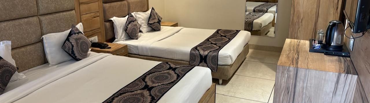 A spacious hotel room with two large beds, a wooden headboard, and minimalist decor.