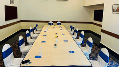 A conference room with a long table, chairs, and notepads at the best resort in Bangalore | Ramanashree California Resort