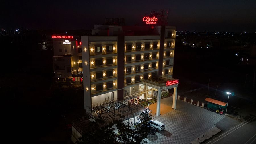 Clarks Collection Somnath hotel illuminated at night with signage visible, parking area and cars in the front of the hotel.
