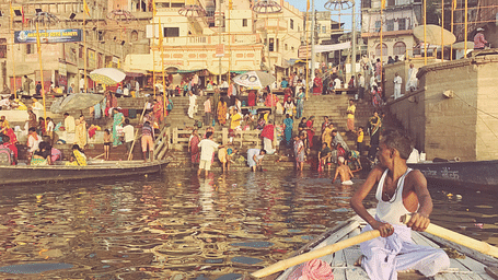 Boats on the Ganges River with people gathered at the ghats in Varanasi.