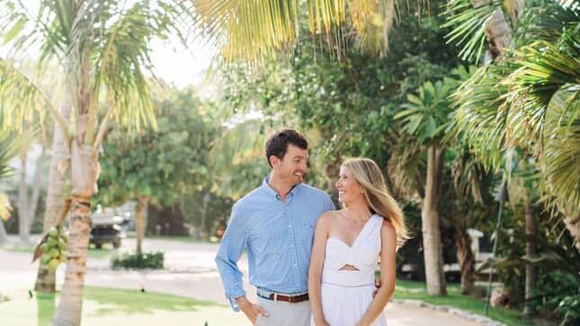 Couple walks down a garden pathway lined with palm trees, holding hands at Abaco Inn.