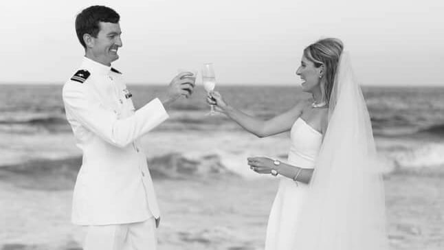 Two people exchange rings on beach during a wedding, guests in the background, Abaco Inn.