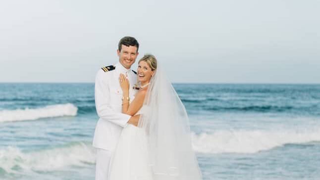 Two people in wedding attire standing on the sand near ocean, Abaco Inn.