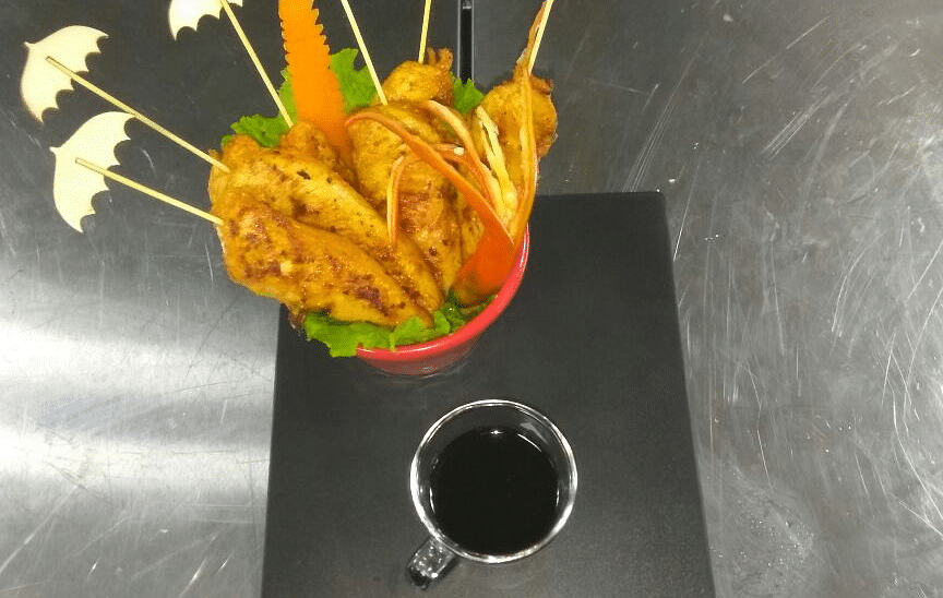 rispy fried chicken skewers with lemon wedges and a side of dipping sauce.