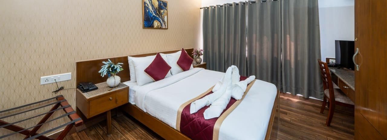 A comfortable bedroom features a neatly made bed with decorative towels and a television for entertainment at Lords Midtown Suites.