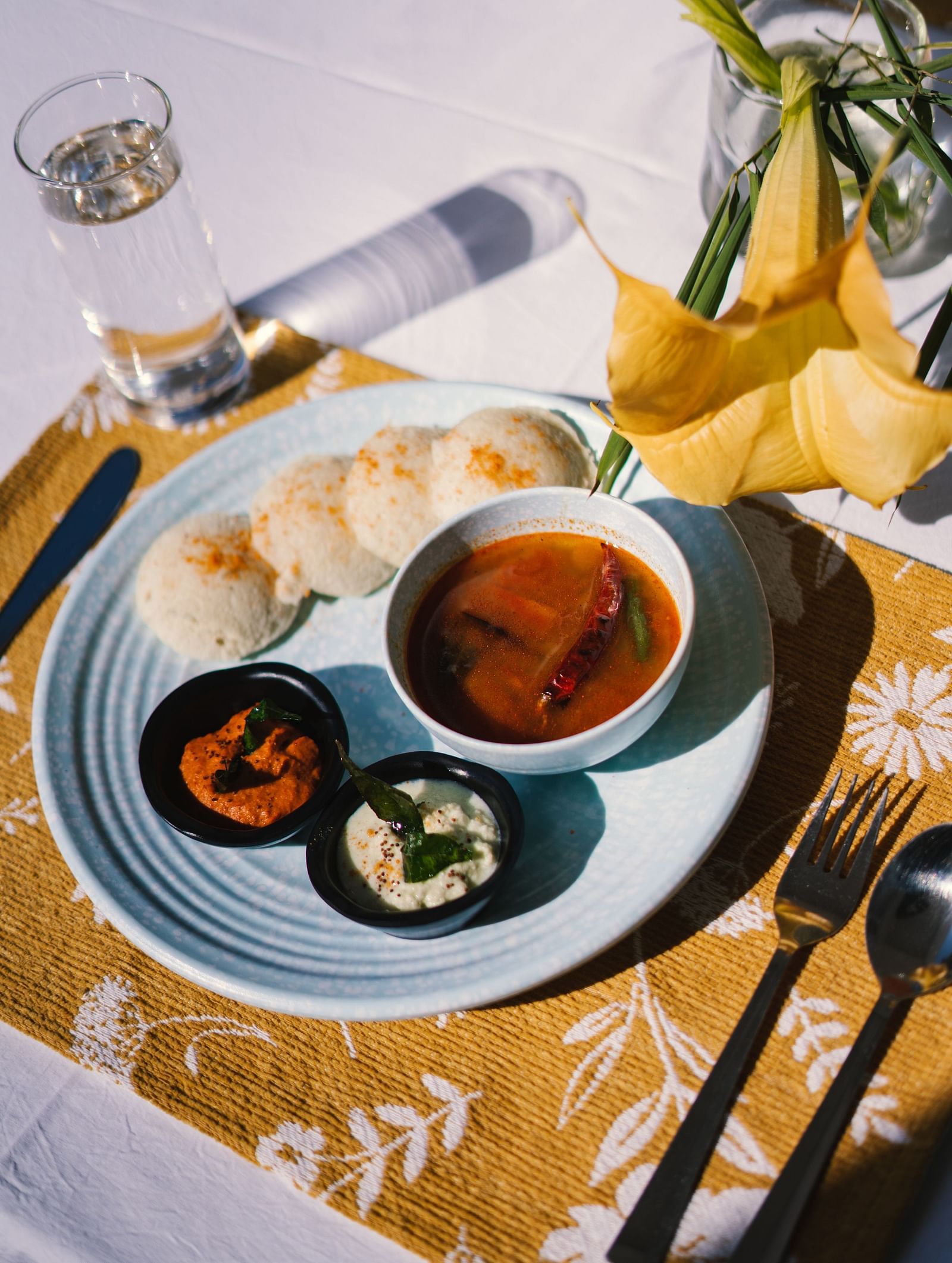A close-up view of a plate with idlis and three bowls of side dishes at BluSalzz Villas - The Green Roof, Bhimtal.