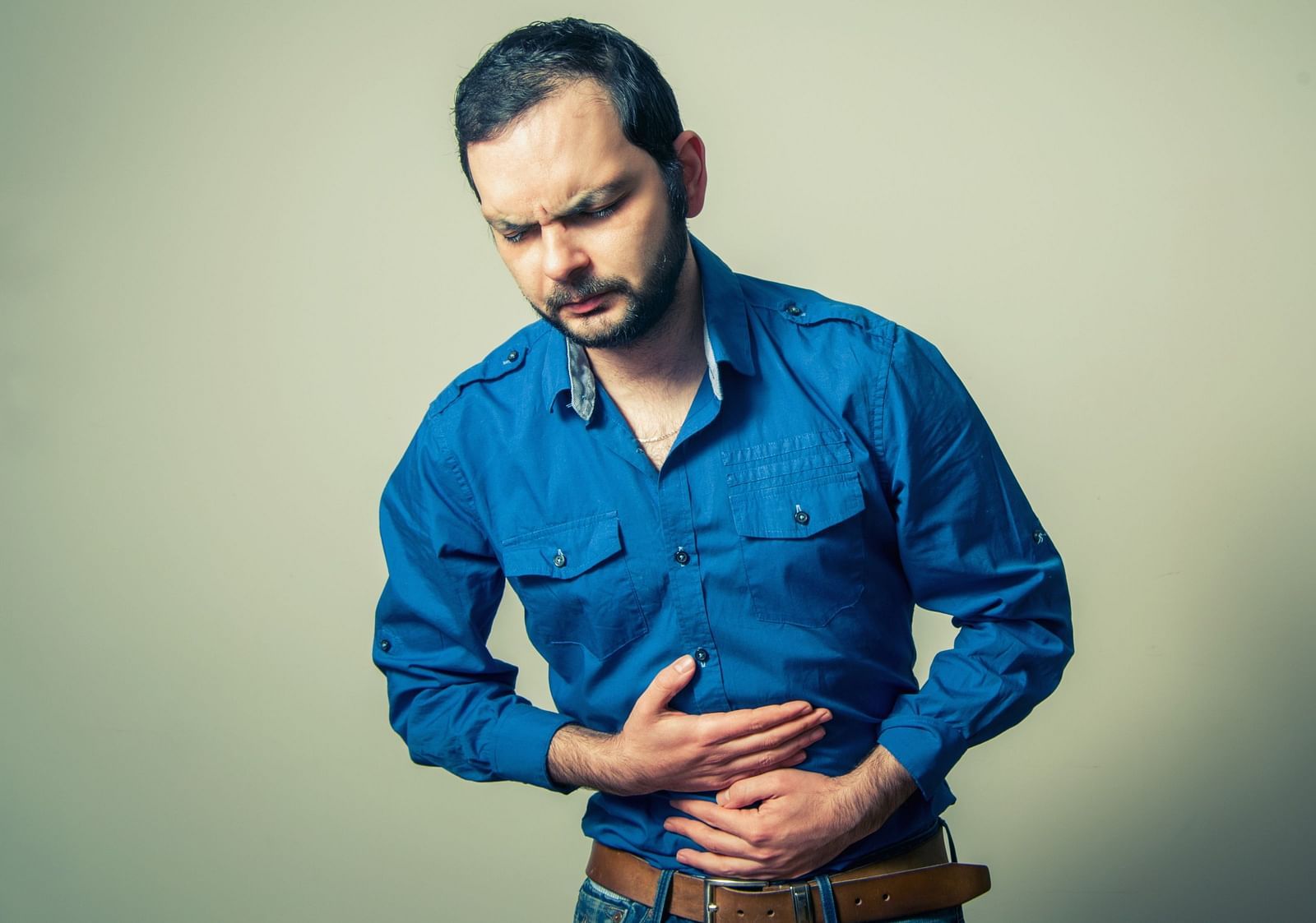 A man clutching his stomach, experiencing an ache - Shreyas Retreat