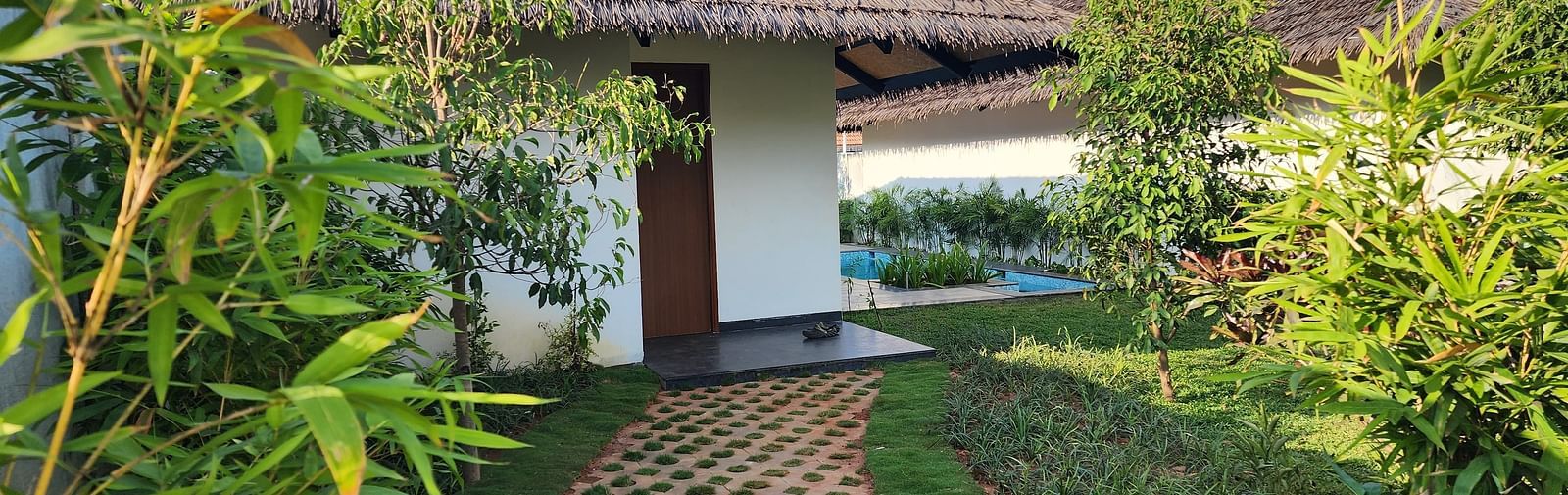 Exterior view of the Exotic Pool Villa with a pathway traversing through a beautiful garden at The Shore, Trishvam.