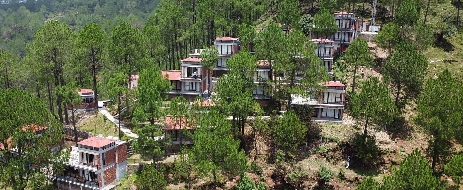 aerial view of the BluSalzz Escapade Resort, Lansdowne surrounded by green trees.