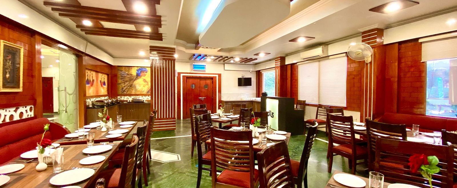 Dining area at DLS Park Grace, Haridwar featuring ample seating area, assorted plates, and bright  lighting.