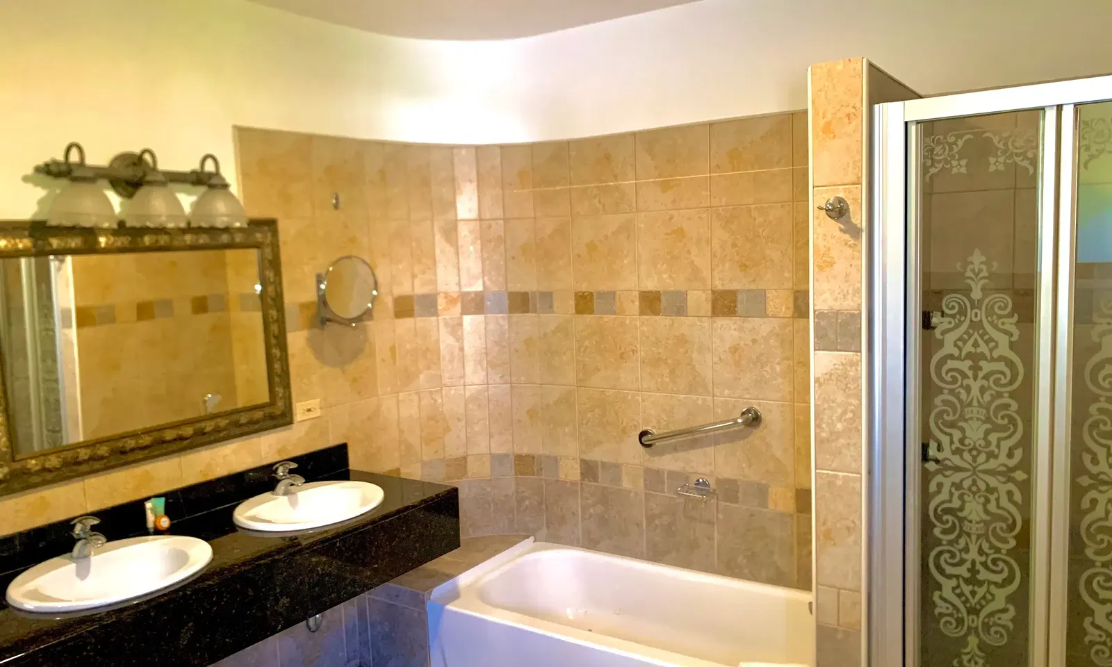 A tiled bathroom shows a bathtub, a vanity with two sinks, and a walk-in shower | Alexander Suite | Altamont Court, Jamaica