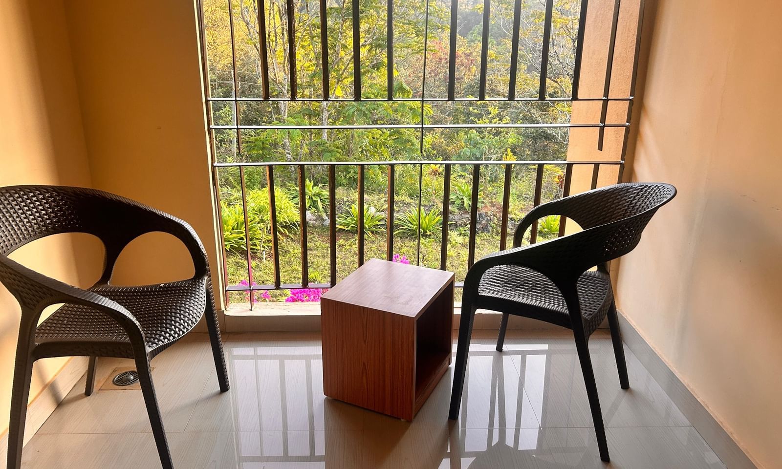 A private balcony with two chairs and a table at Paradise Wild Hills Resort, Kollur, overlooking the beautiful surrounding hills.