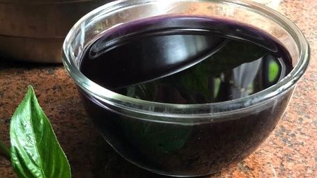 Dark purple Maddh Thopp liquid in a glass bowl.