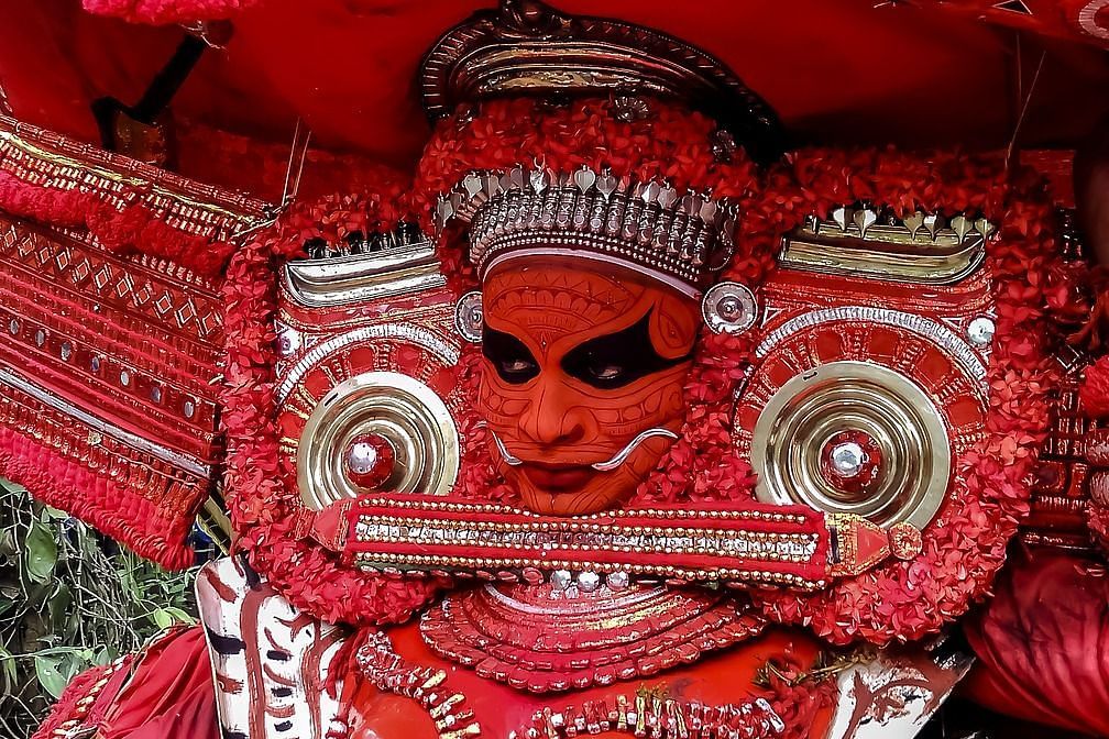 image of a person with orange face painting and heavy ornamental traditional attire