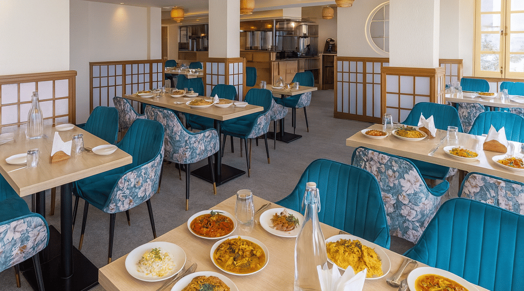 Premium 3-star hotel restaurant in Darjeeling with elegant seating, modern lighting, and tables served with authentic Indian and Chinese cuisine in a bright morning setting