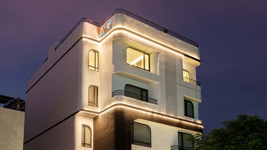 The facade of Indie Stays, Jaipur, glows brightly under night lights against the dark sky.