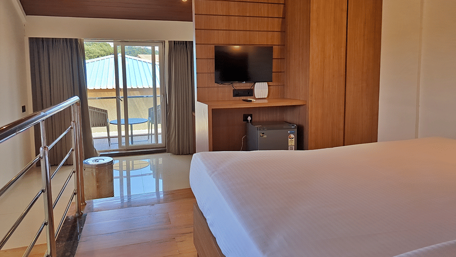 Bedroom with a double bed, television, wooden wardrobe, and railing.