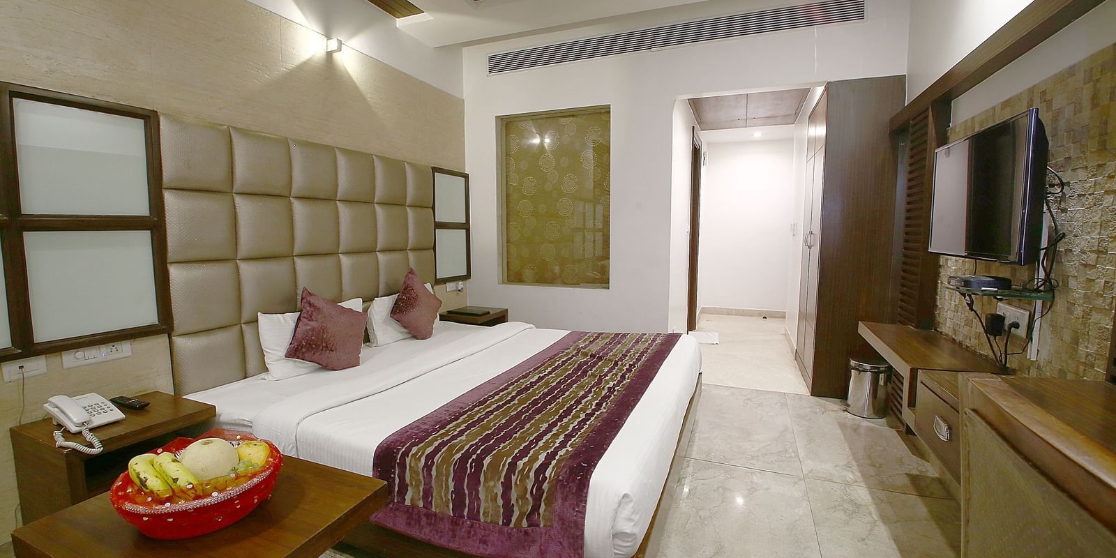 A well-appointed room featuring a king size bed, decorative cushions, and modern furnishings - Hotel Emerald, Chandigarh
